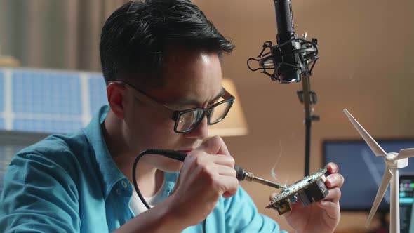 Close Up Of Asian Man With Wind Turbine Fix The Circuit Board While Working Next To The Solar Cell