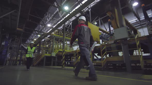 Two Manufacturing Plant Employees Walking along Production Line