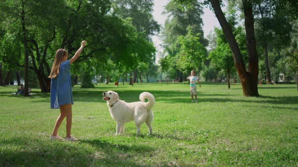 Cute Girl Training Dog in Green Park Rear View