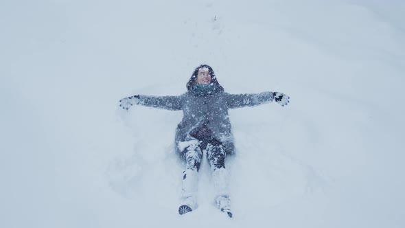 Girl playing with snow and making a snow angel