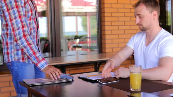 A male customer pays using NFC contactless payment technology on a smartphone.