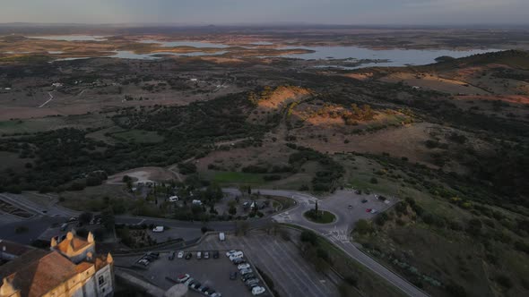 Drone flying over Monsaraz village with Alqueva river in background at dusk, Portugal. Aerial revers