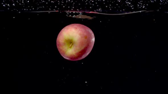 Beautiful red apple being dropped into water in slow motion.