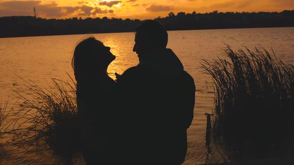 Beautiful Silhouette of Romantic Couple Resting in Caresses at Evening Lake