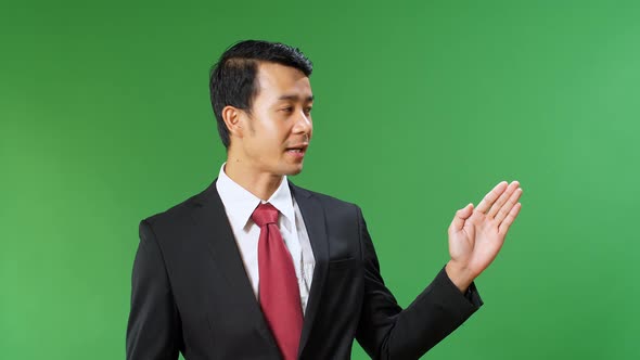 Asian Businessman Pointing On Something And Talking On A Green Screen, Chroma Key