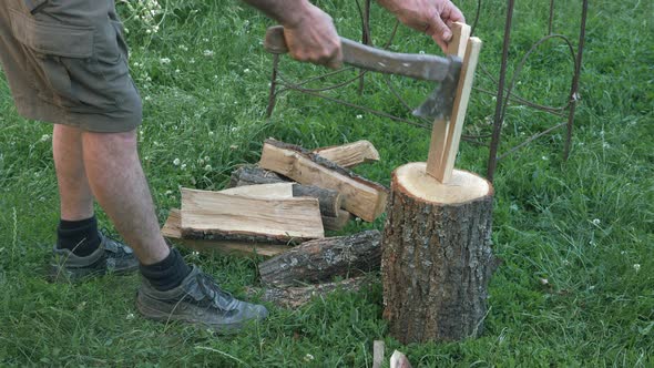 Man chopping wood with ax with green grass on background. Chop wood log with ax