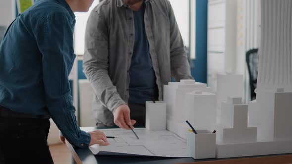 Man and Woman Looking at Blueprints Plan on Paper to Design Building Model and Maquette