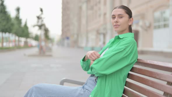 Hispanic Woman Looking at Camera While Sitting on Bench