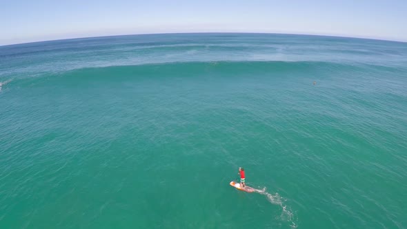 Aerial view of a man sup stand-up paddleboard surfing in Hawaii