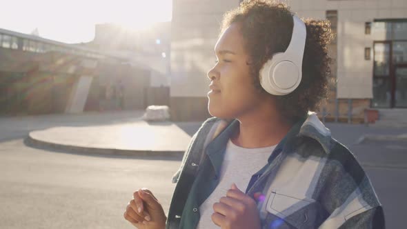 Girl Listening to Music in Earphones in Sunlight