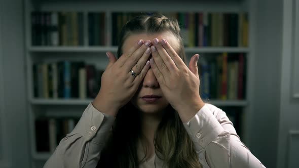 Portrait of a Young Caucasian Woman Who Closes Eyes By Hands in the Indoors