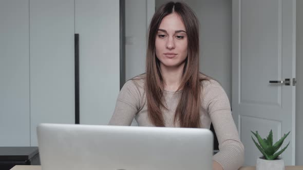 Young Bored Businesswoman with Laptop Sitting By Table at Home and Making Head Massage in Modern