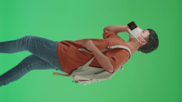 Asian Boy Student Wearing A Mask, Talking On Mobile Phone While Running To School On Green Screen