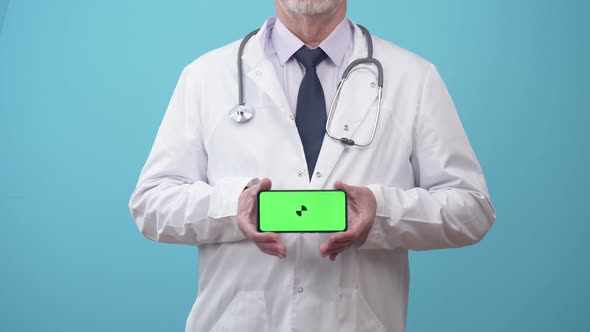 Man Doctor in Medical Gown Shows a Phone Screen with an App Closeup