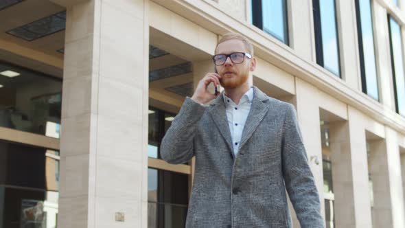 Confident Male Entrepreneur Talking on Smartphone Walking Near Business Center