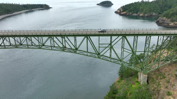 Single car driving across the green steel bridge at Deception Pass State Park.