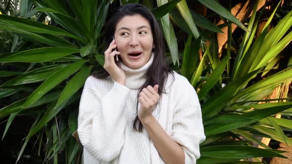 Young Asian Woman Use the Phone with Earphones While Walking