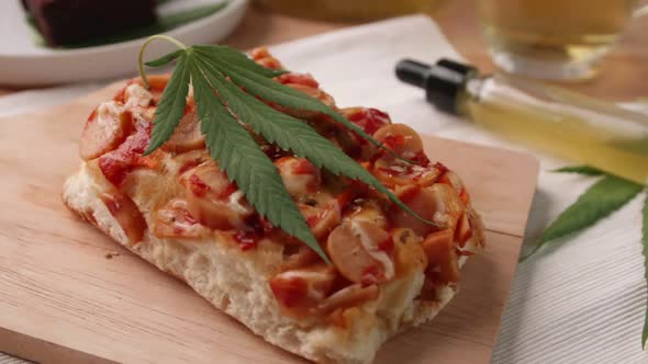 Homemade pizza with marijuana or cannabis leaf on wooden tray.