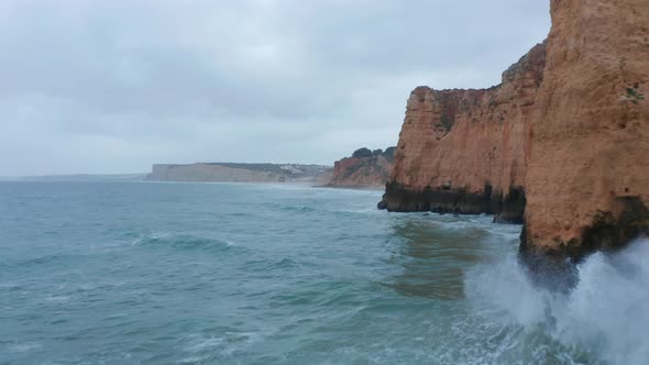 Aerial Drone Flying Low Above Ocean Waves By High Orange Colored Cliffs Lagos Algarve Portugal Dolly