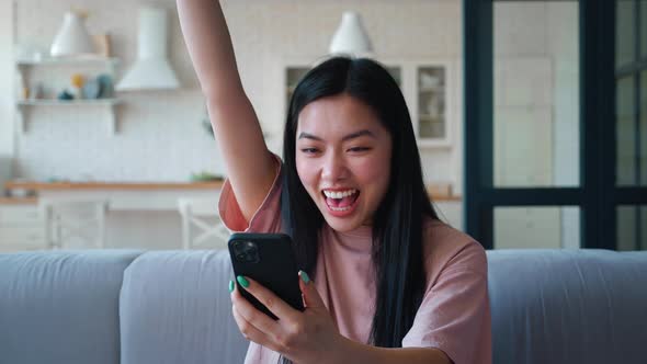 Closeup of an Attractive Asian Ethnicity Woman Sitting on Sofa at Living Room Typing Text Into