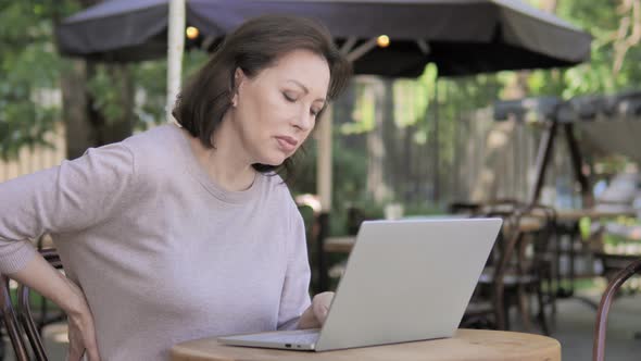 Old Woman with Back Pain Working on Laptop Outdoor