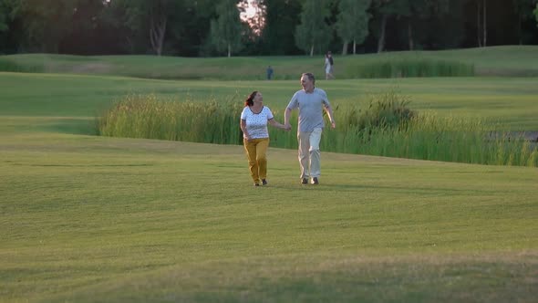 Happy Senior Couple Running on Green Lawn.