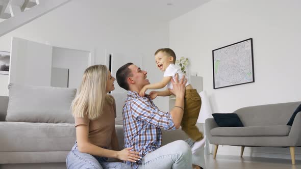 Happy Young Family Couple Having Fun Playing with Cute Toddler Kid Son at Home