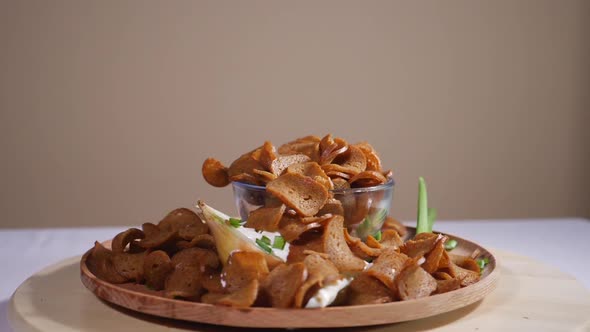 Tasty bread crackers with onion and sour cream on a wooden plate