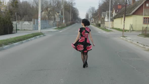 Attractive Young Woman in a Dress with Flowers Running on the Highway