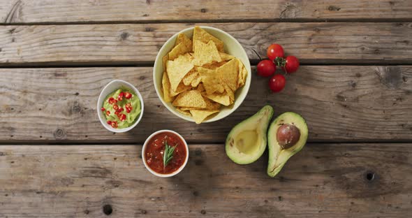 Video of tortilla chips, guacamole and salsa dip on a wooden surface