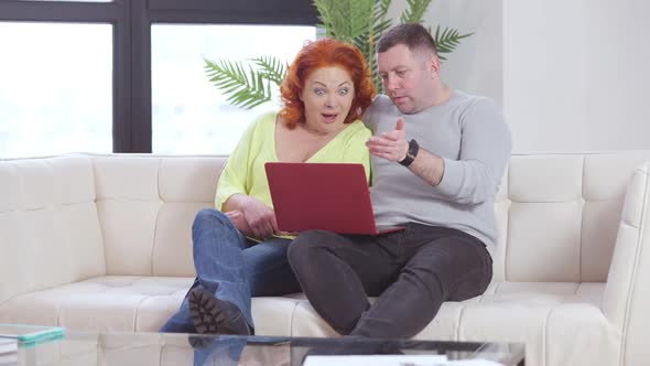 Wide Shot of Excited Caucasian Husband and Wife Rejoicing Good News Checking Email on Laptop at Home