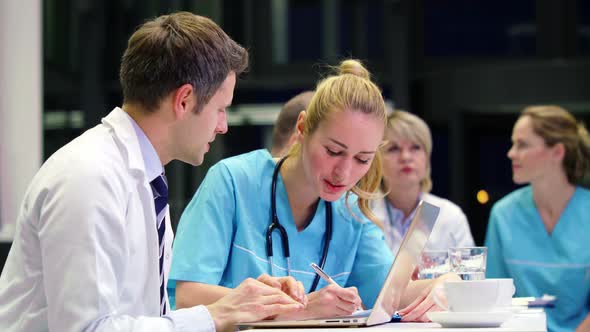 Doctors and nurse discussing with each other in conference room