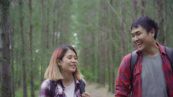 Asian backpacker couple on hiking adventure freedom walking in forest, holidays near lots of tree.