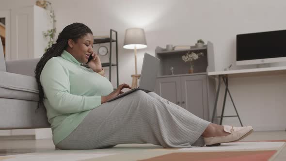 African-American Businesswoman Working on Laptop while Talking on Phone