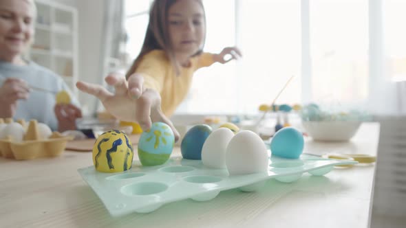 Girl and Grandmother Dying Easter Egg and Putting It on Tray