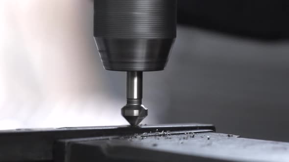 Detail steel bars being drilled by a drill press to create a structure in a machine shop.