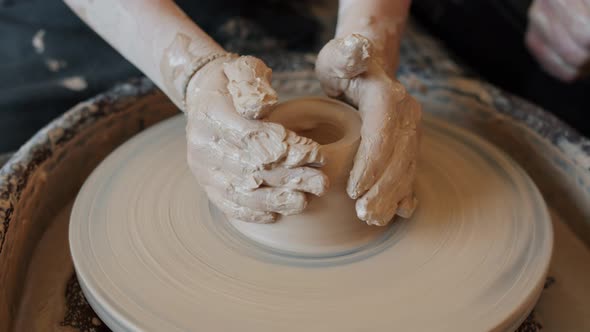 Close-up of Kid's Hands Working with Clay on Throwing Wheel Shaping Pot