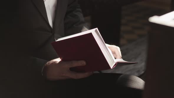 Unrecognizable Man Reading Bible while Sitting in Church