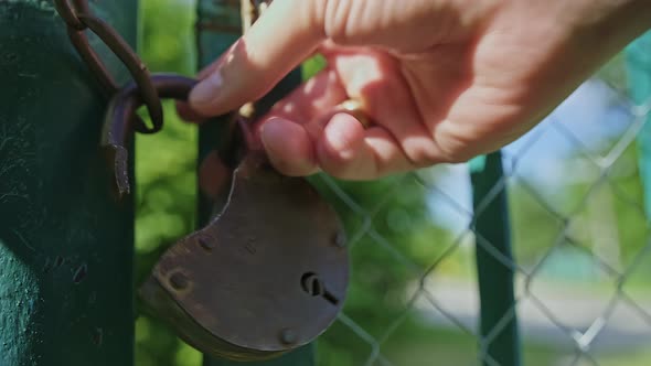 Closeup of a Caucasian Man is Struggling to Open an Old Padlock with Hands