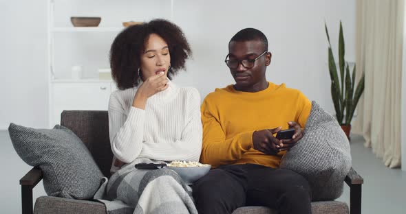 Afro American Couple Friends Girl and Guy Sitting Together in Living Room Eating Popcorn Listening