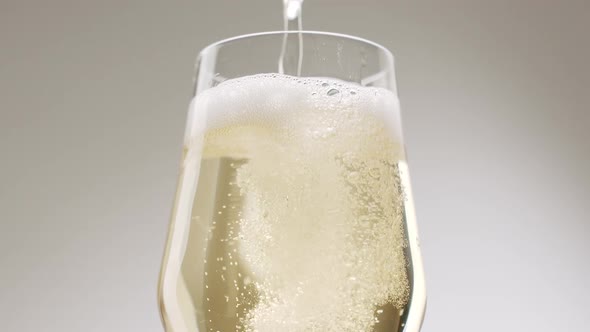 The Champagne Bottle is Poured Into the Sparkling Glass on a White Background