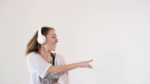 Young Cool Girl in Wireless Headphones Dancing in Studio