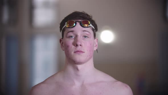 A Man Swimmer Puts on His Goggles and Looks in the Camera