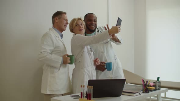 Cheerful Diverse Multiethnic Healthcare Workers in Lab Coat Posing for Selfie Shot at Medical Office