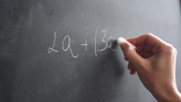 Woman's Hand with Chalk Writes a Formula on a Blackboard