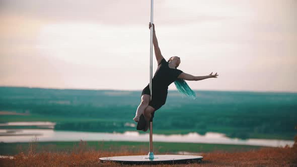 Woman in Long Dress with Blue Braids Spinning on the Pole