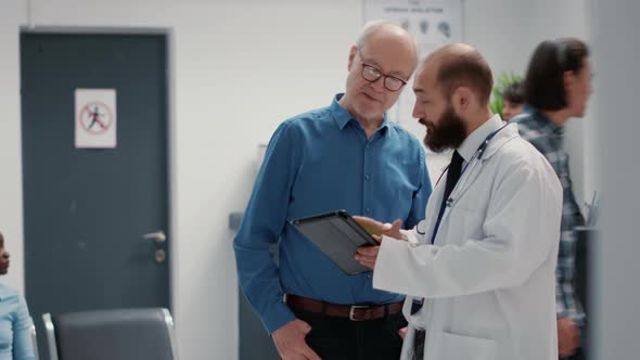 Male Physician Doing Consultation with Retired Man in Hospital Reception