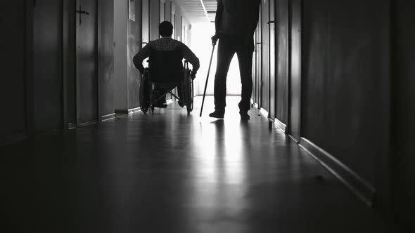 Silhouettes of Disabled Patients in Hospital Corridor