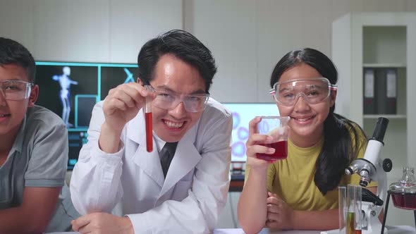 Young Asian Boy, Girl And Teacher Smiling While Holding Test Tubes. Study With Scientific Equipment