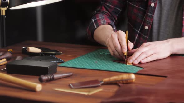 Man Tailor Cutting Artificial Leather with Ruler Closeup